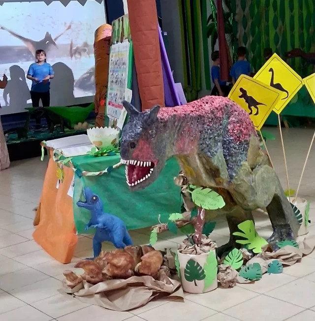 MUESTRA DE DINOSAURIOS EN EL NIVEL PRIMARIO DEL IMA  El profesor Eduardo Aranela, del Instituto María Auxiliadora de Rawson, presentó junto a los estudiantes de tercer grado una nueva edición de la tradicional Muestra de Dinosaurios.  El proyecto integra varias áreas: clasificación de dinosaurios en Ciencias Naturales, investigación e infografías en Lengua y armado de maquetas con materiales reciclados en Tecnología. Las familias acompañan el proceso y colaboran en la presentación final.  Aranela destacó el entusiasmo de los chicos, quienes cada año llegan con gran interés y conocimientos previos, fortalecidos por visitas al museo y trabajos anteriores.